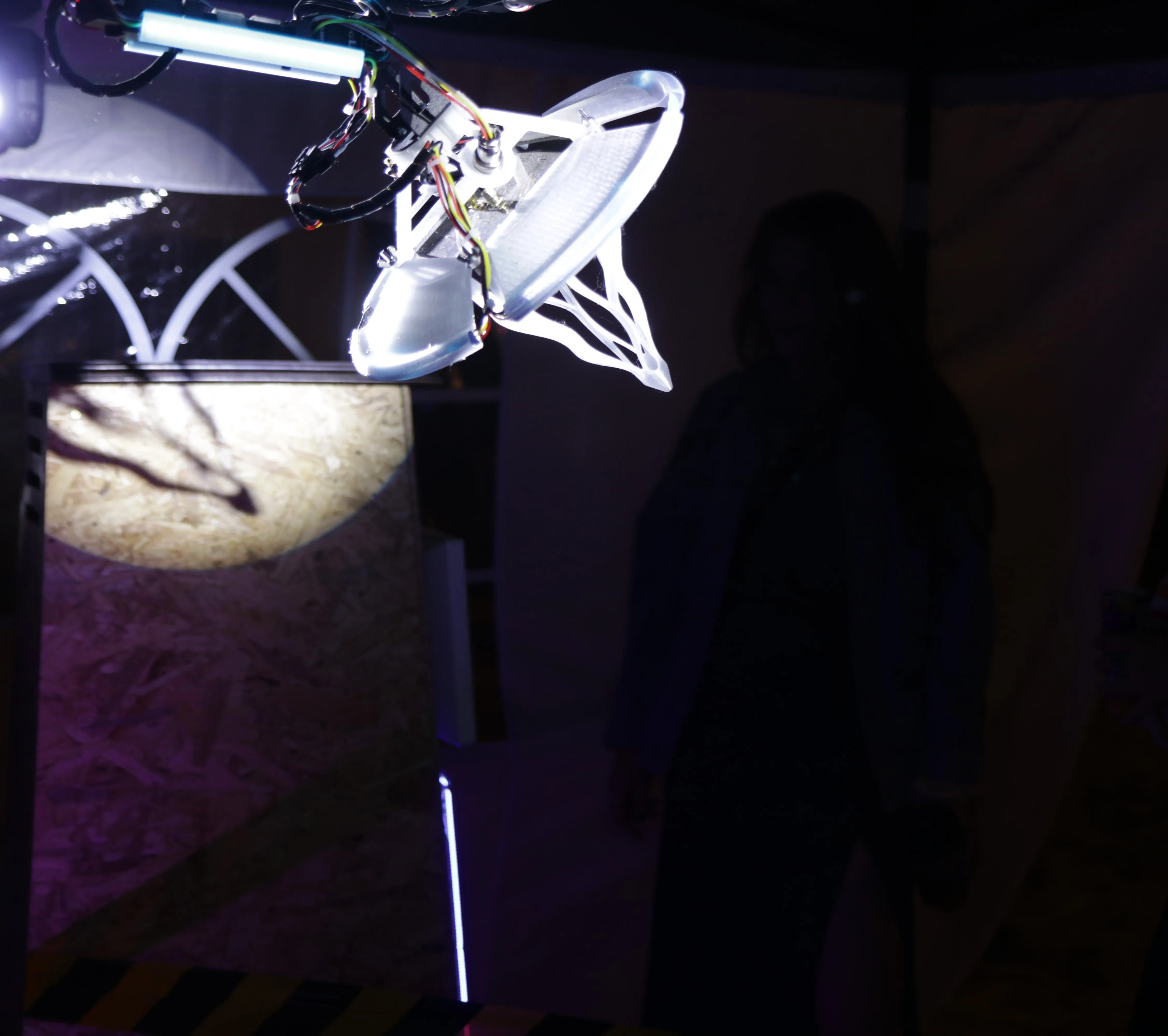 The arm and antenna picked out by a moving-head spotlight beam against the dark gazebo.